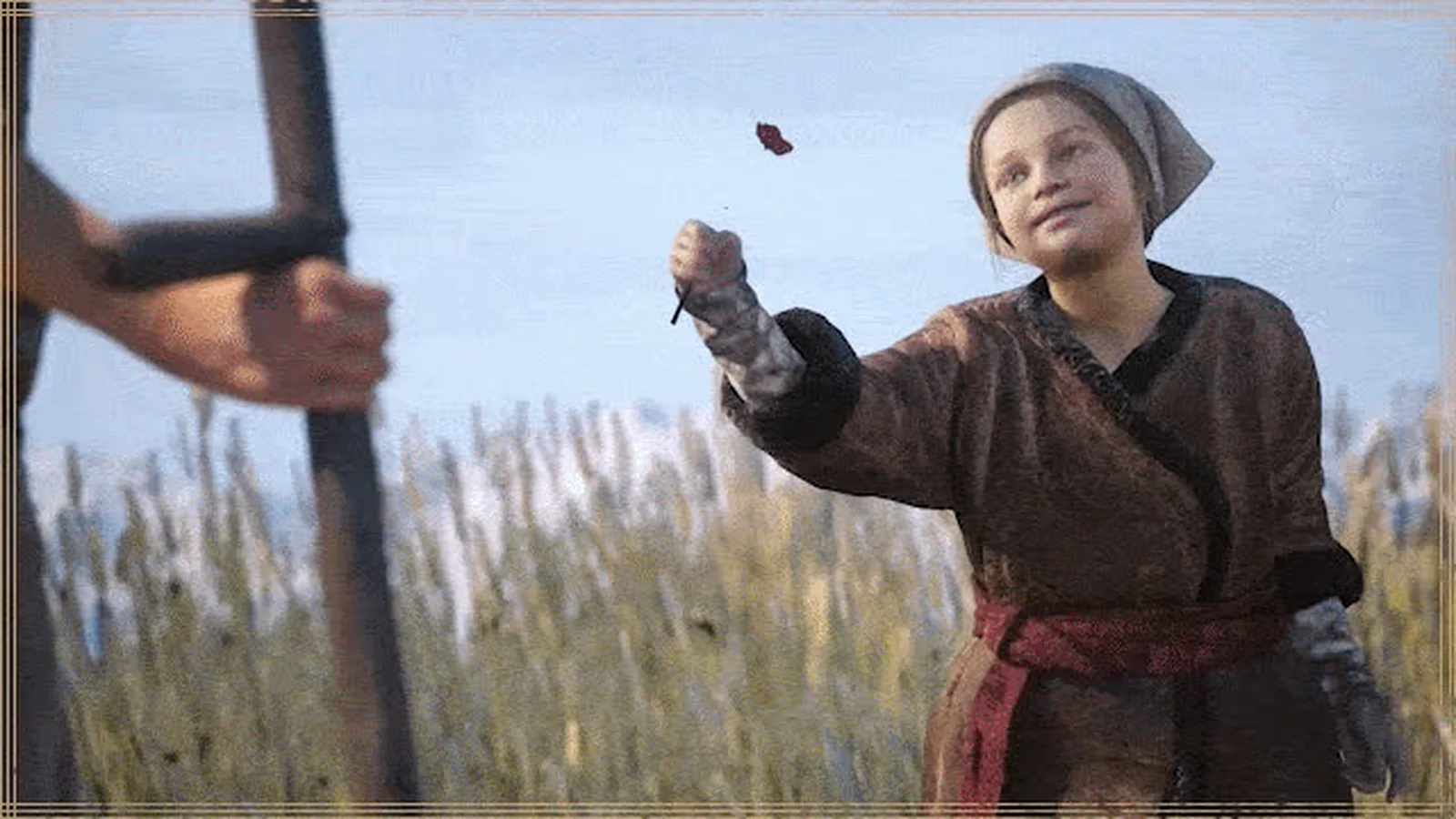 Lunka holds up a red flower petal in a sunlit field